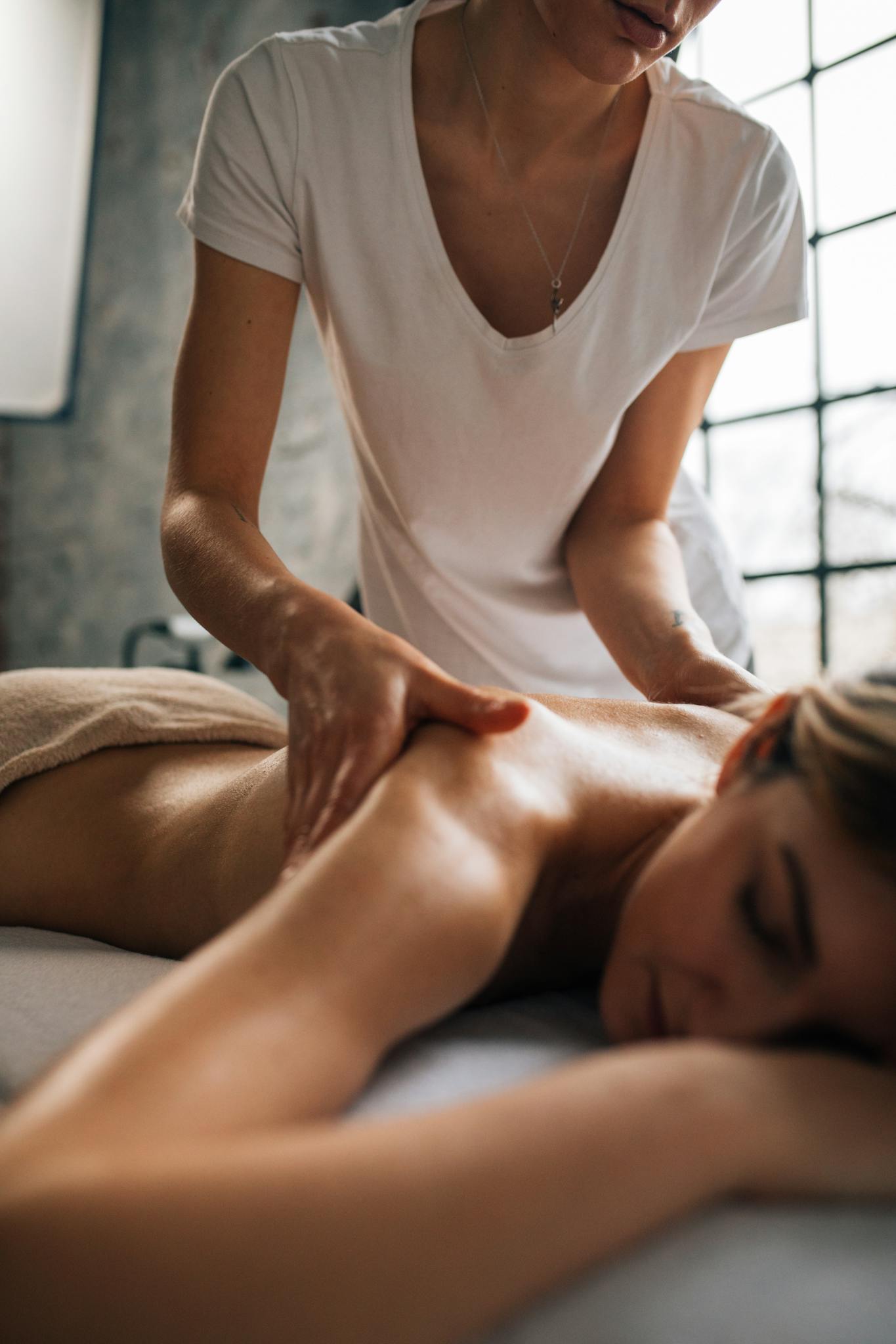 Woman receiving a relaxing shoulder massage in a tranquil spa room. Perfect for wellness and relaxation themes.